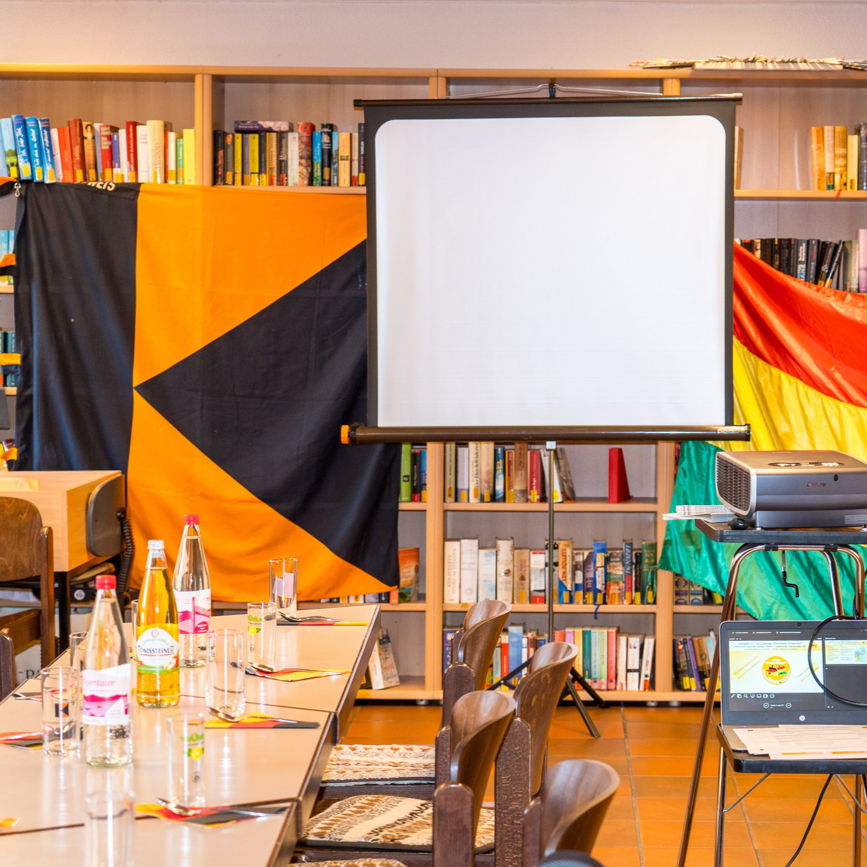 Mit Kolpingbanner und Bolivienfahne geschmückter Raum inkl. Beamer, Leinwand und gedecktem Tisch