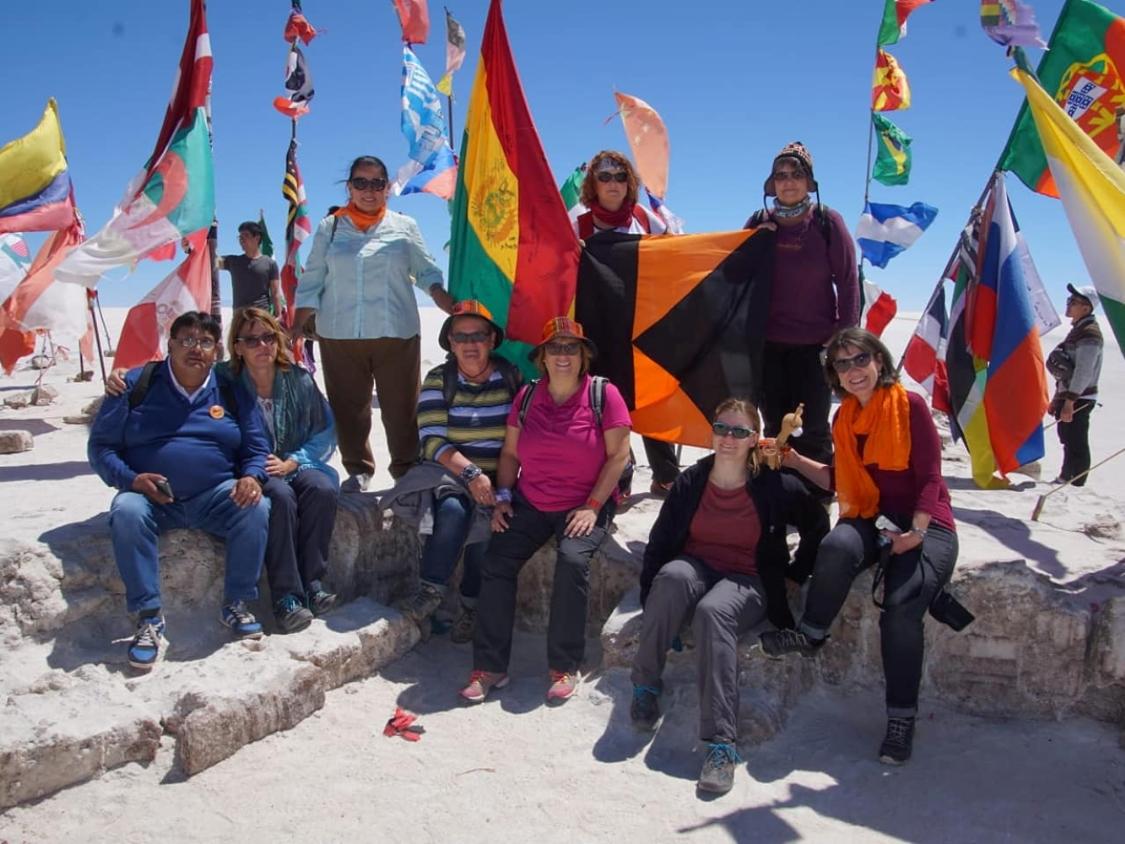 Gruppenfoto in der Salzwüste Salar de Uyuni mit vielen bunten Fahnen im Hintergrund