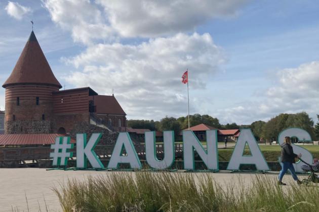 Schriftzug  mit den Buchstaben KAUNAS auf einem Platz, im Hintergrund die Burg von Kaunas, Litauen