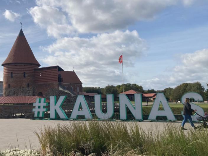 Schriftzug  mit den Buchstaben KAUNAS auf einem Platz, im Hintergrund die Burg von Kaunas, Litauen