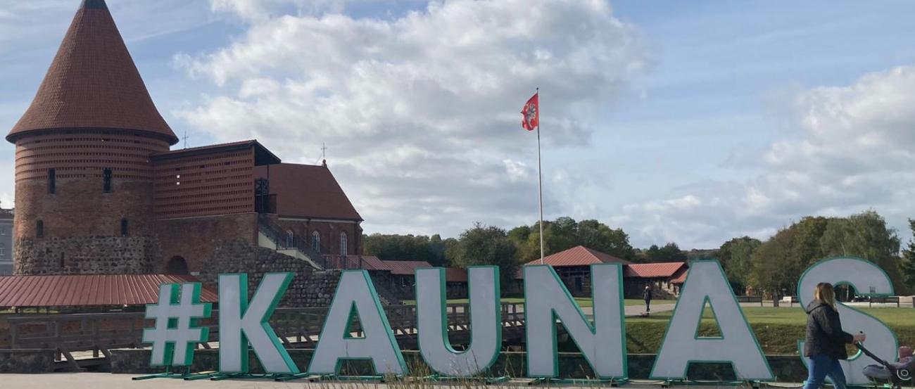 Schriftzug  mit den Buchstaben KAUNAS auf einem Platz, im Hintergrund die Burg von Kaunas, Litauen