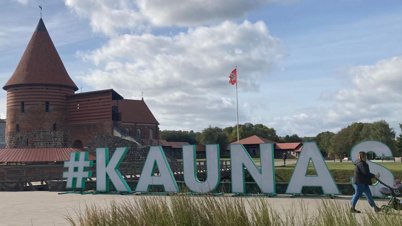 Schriftzug  mit den Buchstaben KAUNAS auf einem Platz, im Hintergrund die Burg von Kaunas, Litauen