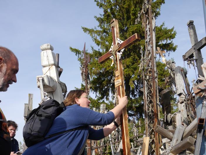 Das Bild zeigt drei Menschen, die ein neues Kreuz inmitten vieler anderer Kreuze aufstellen.