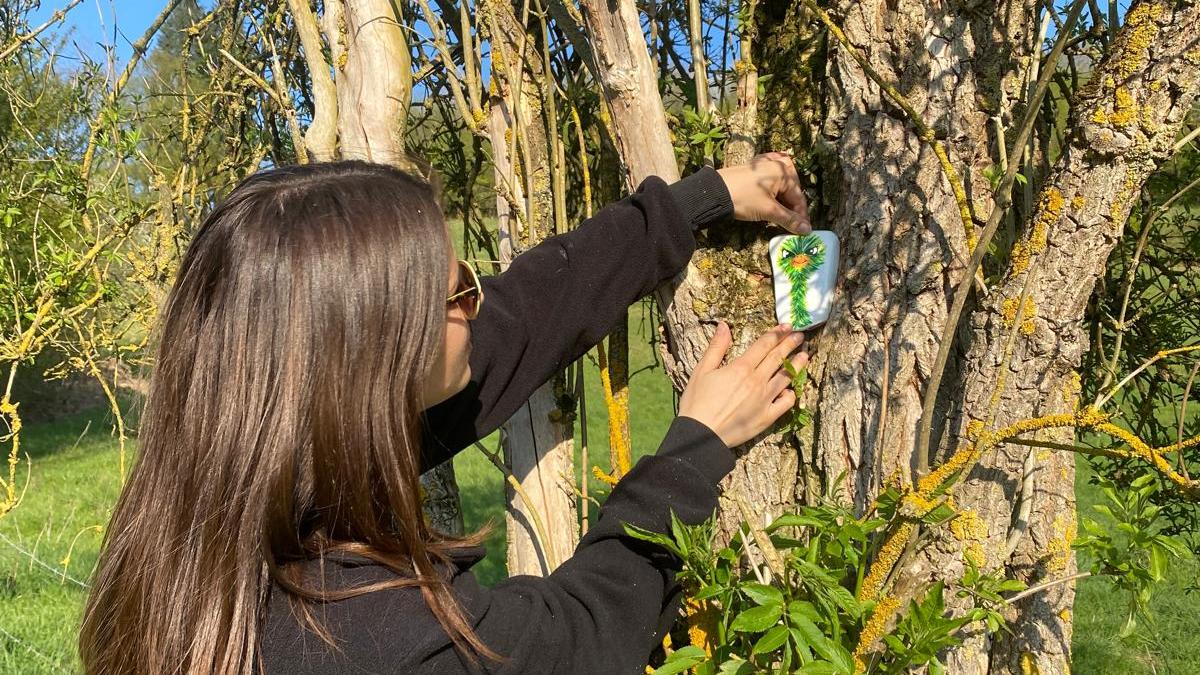 Eine Frau schmückt einen Baum auf dem Kulturweg.