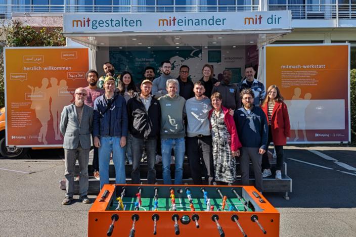 Eine Gruppe von Menschen steht vor dem Mitmachmobil des Kolping-Netzwerkes für Geflüchtete.