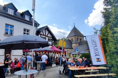 Dorfplatz mit Biertischen und Menschen, die fröhlich feiern.