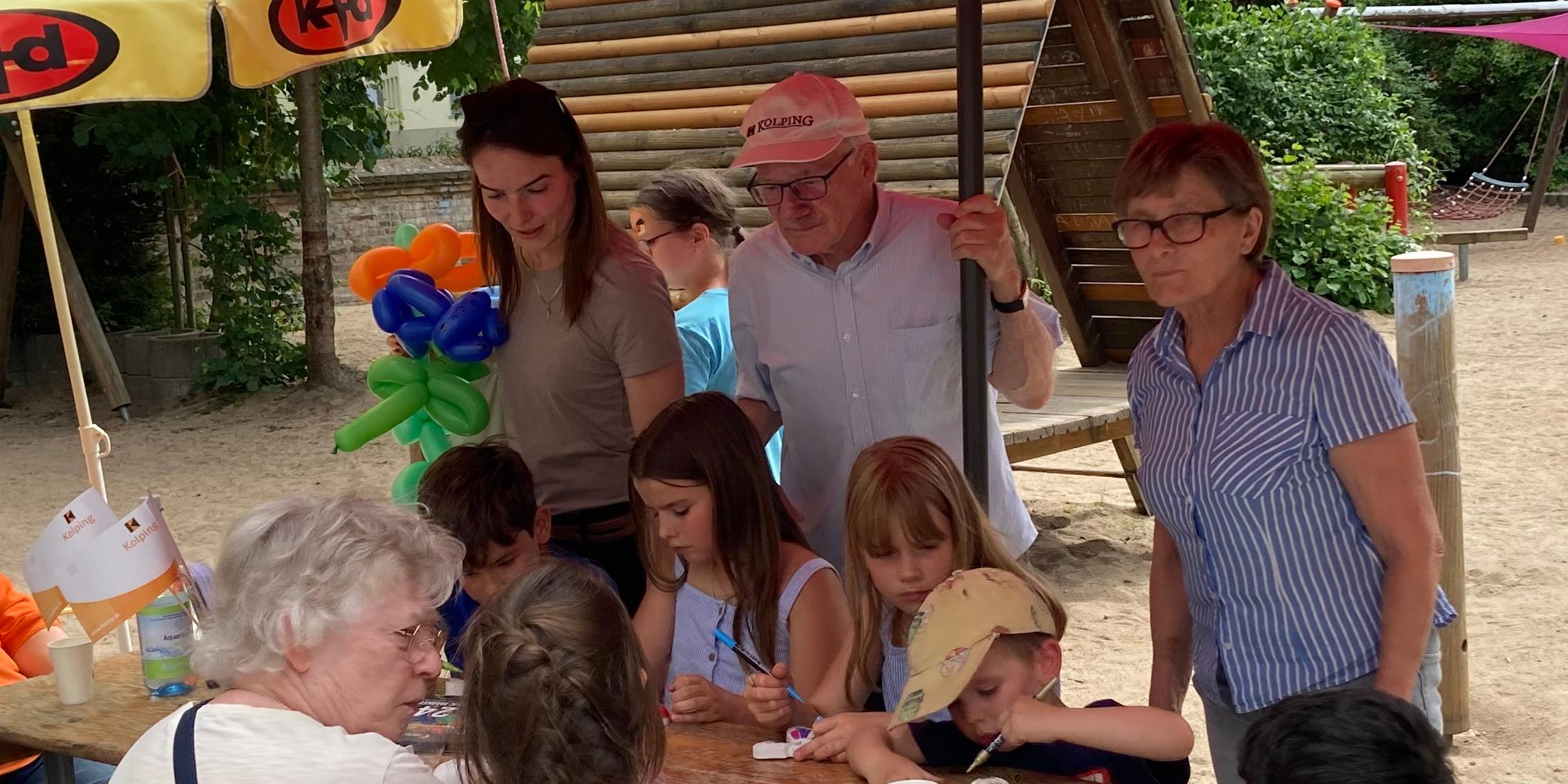 Kinder basteln an einem Holztisch mit Erwachsenen