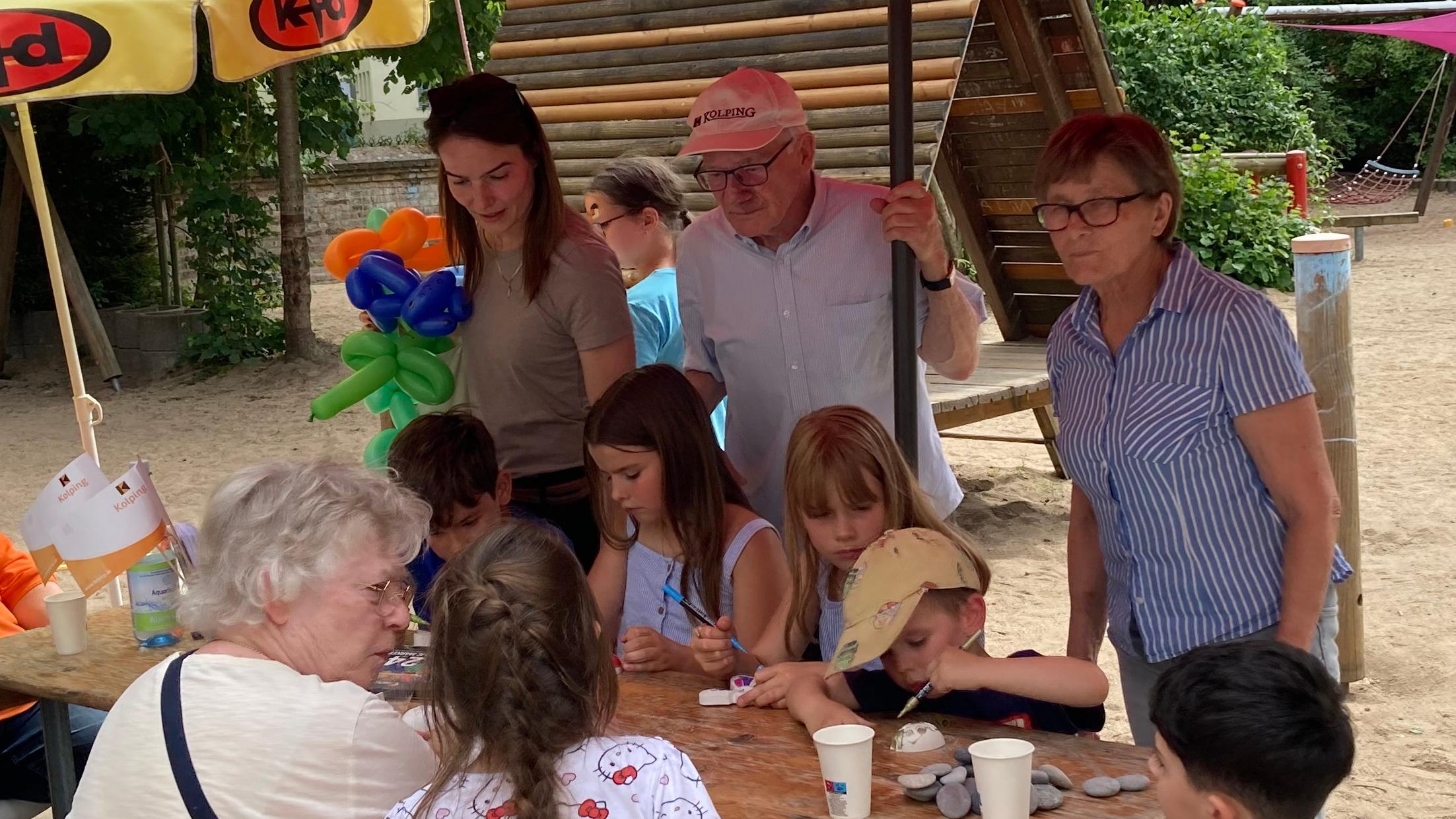 Kinder basteln an einem Holztisch mit Erwachsenen