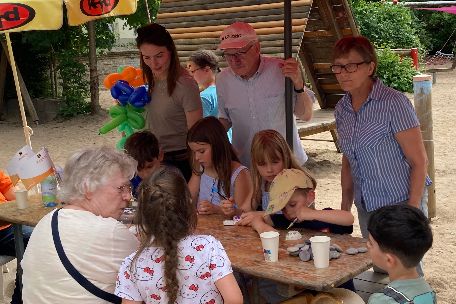 Kinder basteln an einem Holztisch mit Erwachsenen