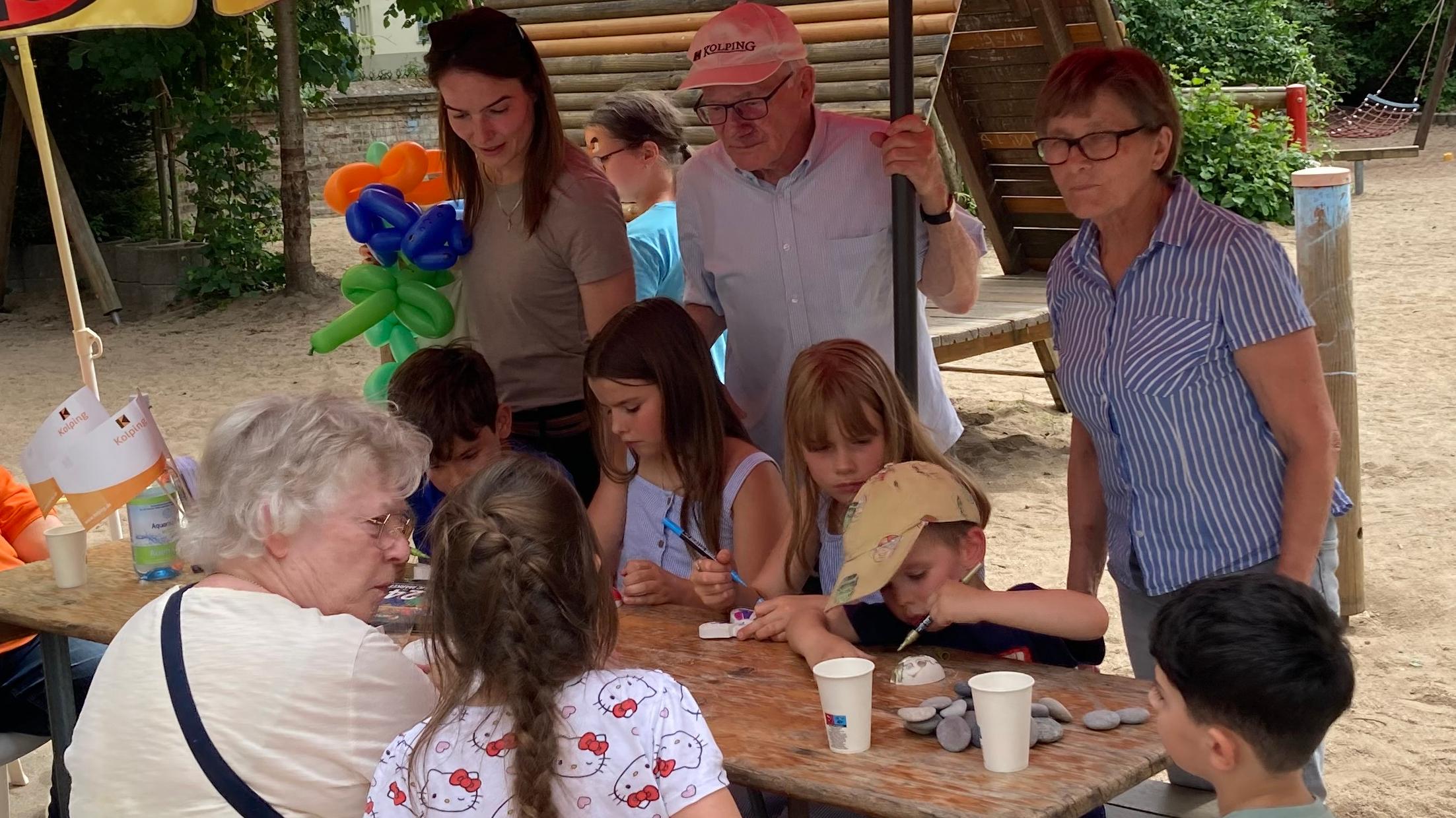 Kinder basteln an einem Holztisch mit Erwachsenen