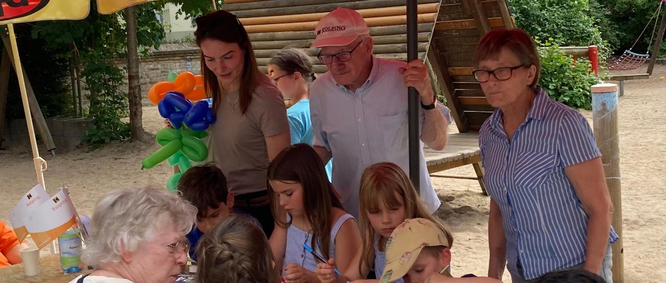 Kinder basteln an einem Holztisch mit Erwachsenen