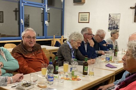 Menschen sitzen am Tisch und unterhalten sich