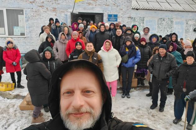 Vor einem Haus im Schnee steht eine Gruppe von Menschen für ein Selfie.