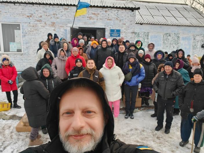 Vor einem Haus im Schnee steht eine Gruppe von Menschen für ein Selfie.