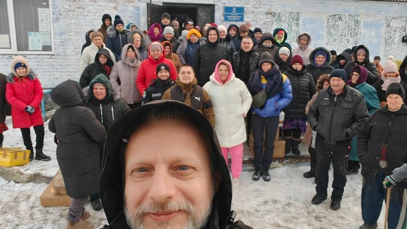 Vor einem Haus im Schnee steht eine Gruppe von Menschen für ein Selfie.