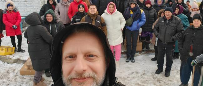 Vor einem Haus im Schnee steht eine Gruppe von Menschen für ein Selfie.