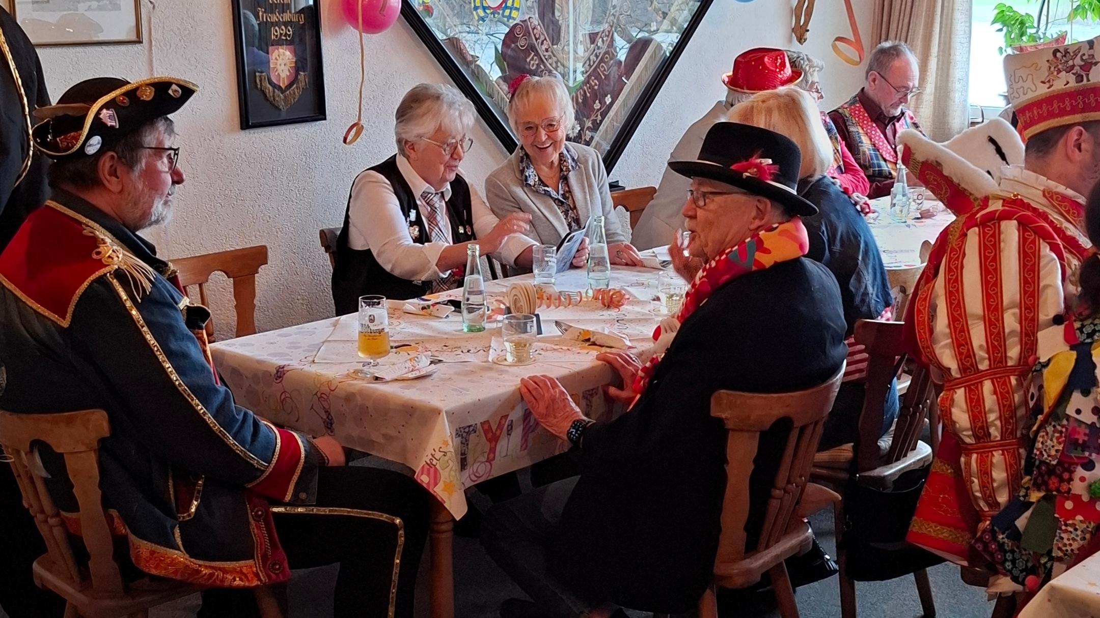 ein karnevalistisch geschmückter Raum, am Tisch sitzen verkleidete Menschen