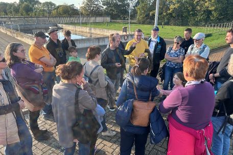Mitglieder der Kolpingsfamilie hören einen Vortrag neben der Kläranlage zu
