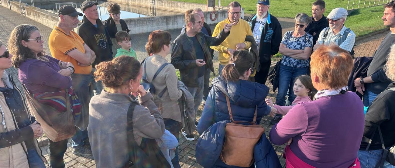 Mitglieder der Kolpingsfamilie hören einen Vortrag neben der Kläranlage zu