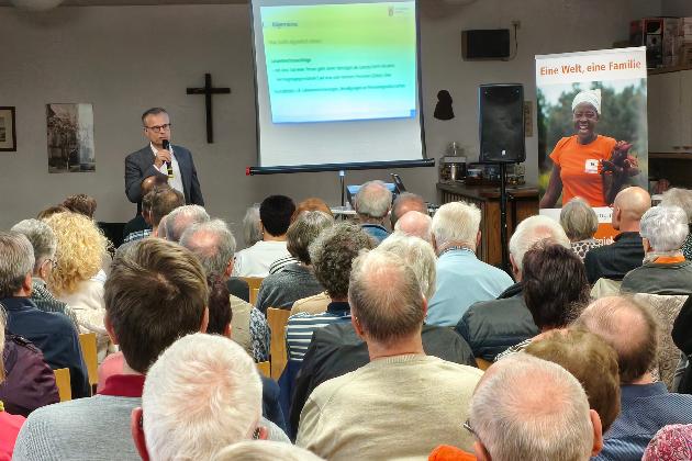 Das Bild zur Infoveranstaltung zeigt das Publikum von hinten, vorne steht der Referent neben einer Leinwand.