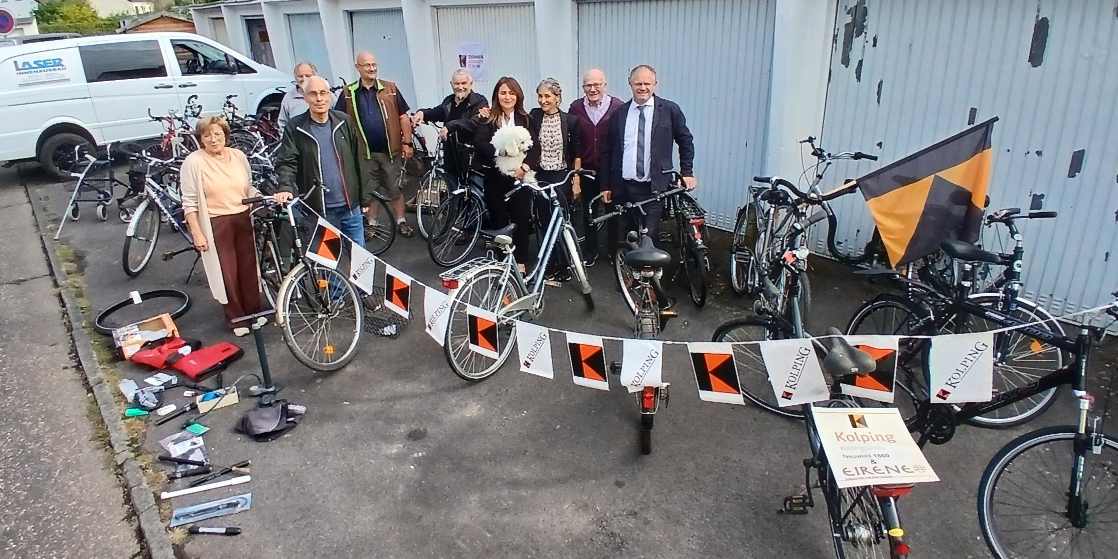 Gruppenfoto, im Hintergrund Garagen, im Vordergrund gesammelte Fahrräder