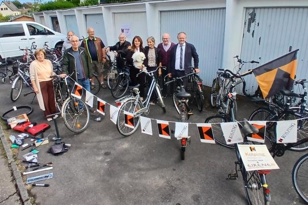 Gruppenfoto, im Hintergrund Garagen, im Vordergrund gesammelte Fahrräder