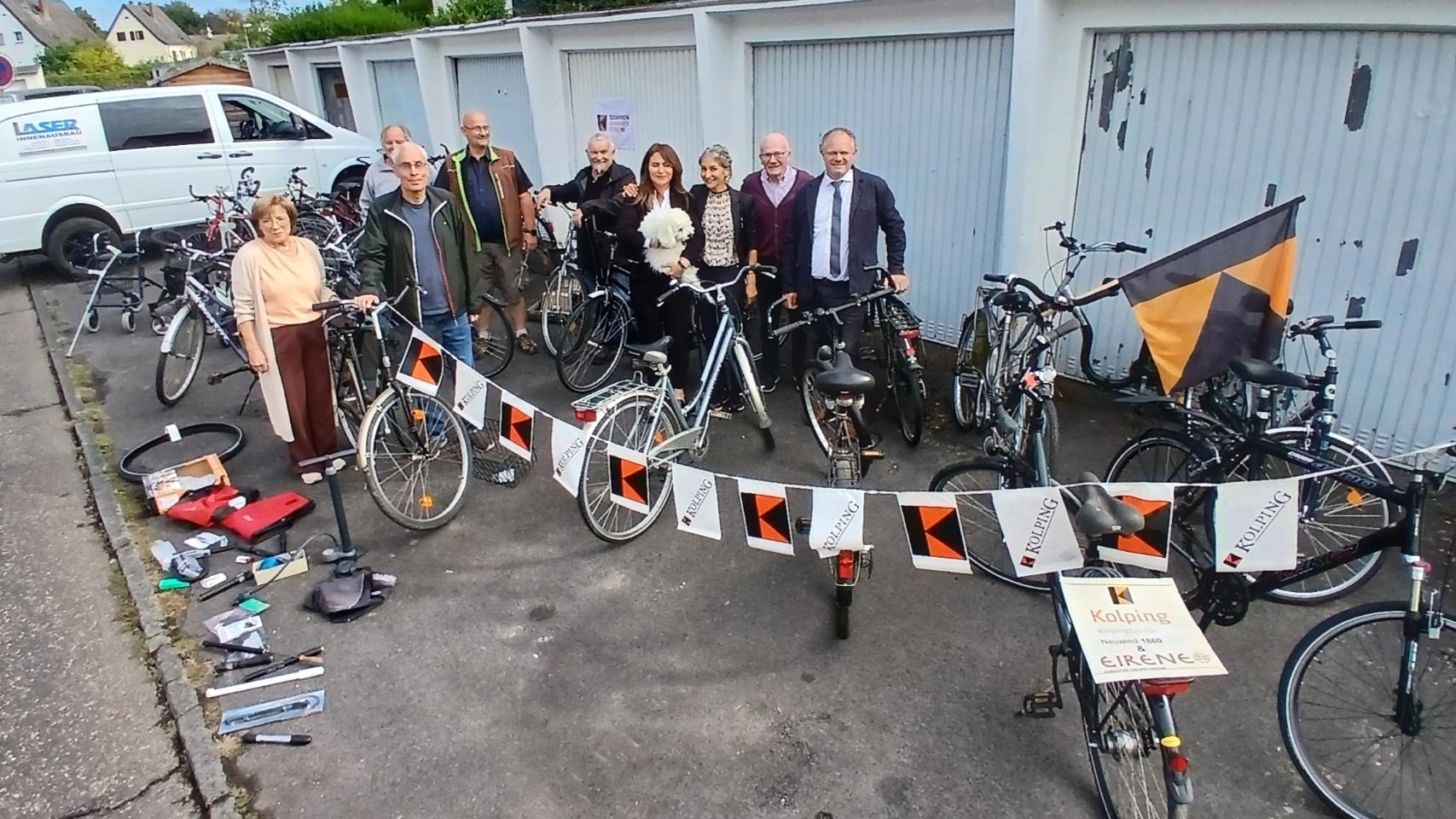 Gruppenfoto, im Hintergrund Garagen, im Vordergrund gesammelte Fahrräder