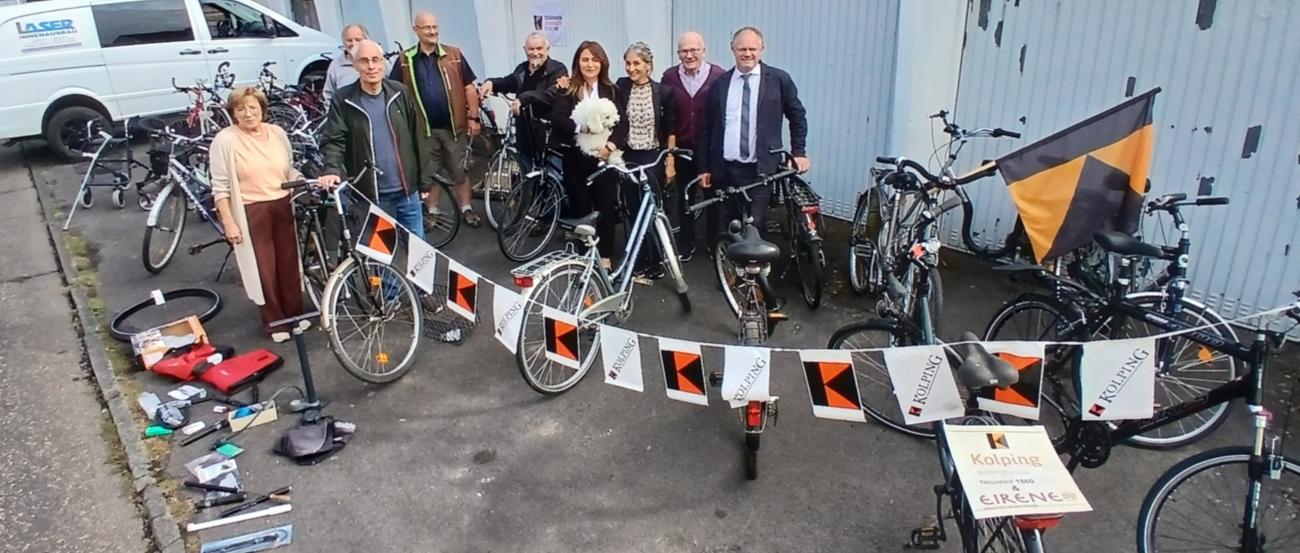 Gruppenfoto, im Hintergrund Garagen, im Vordergrund gesammelte Fahrräder
