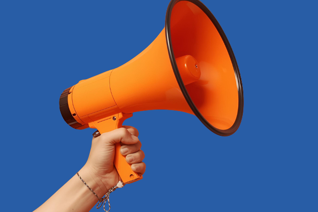 Hand, die ein oranges Megaphon hält vor dunkelblauem Hintergrund