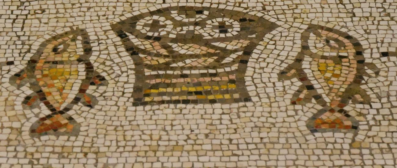 Steinmosaik in Beige- und Brauntönen, das einen Korb mit Broten in der Mitte und an jeder Seite einen Fisch zeigt.