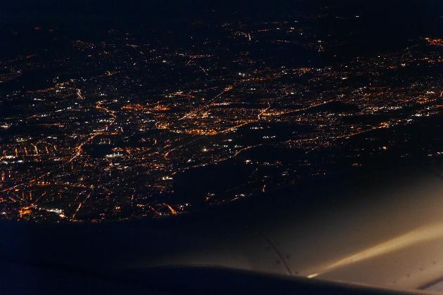 Blick aus einem Flugzeug bei Nacht auf die Lichter einer großen Stadt