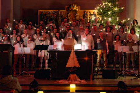Ein großer Chor steht zusammen im Altarraum, jeder hält eine Kerze in der Hand