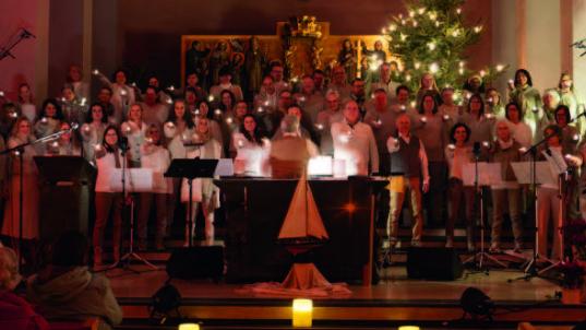 Ein großer Chor steht zusammen im Altarraum, jeder hält eine Kerze in der Hand