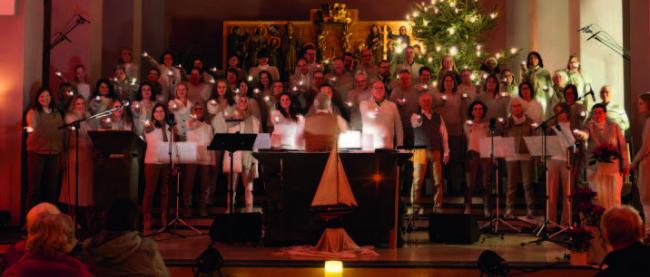 Ein großer Chor steht zusammen im Altarraum, jeder hält eine Kerze in der Hand