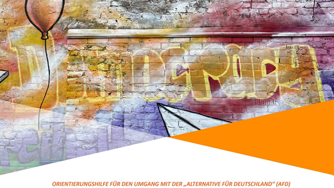 Bild einer bunt besprühten Ziegelmauer mit dem Schriftzug Democracy