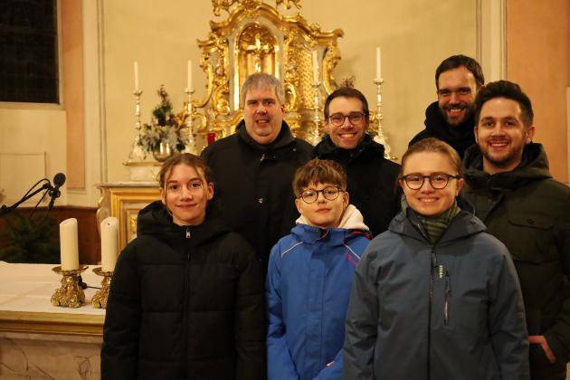 Teilnehmer des Gottesdienstes stehen vor dem Altarraum in der Kirche
