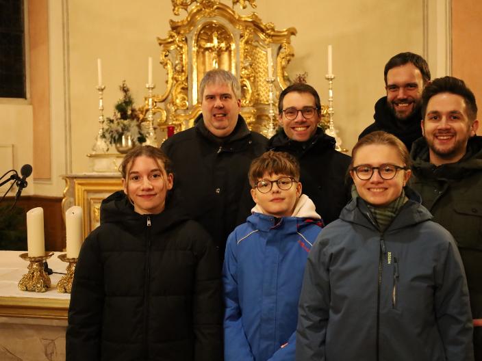 Teilnehmer des Gottesdienstes stehen vor dem Altarraum in der Kirche