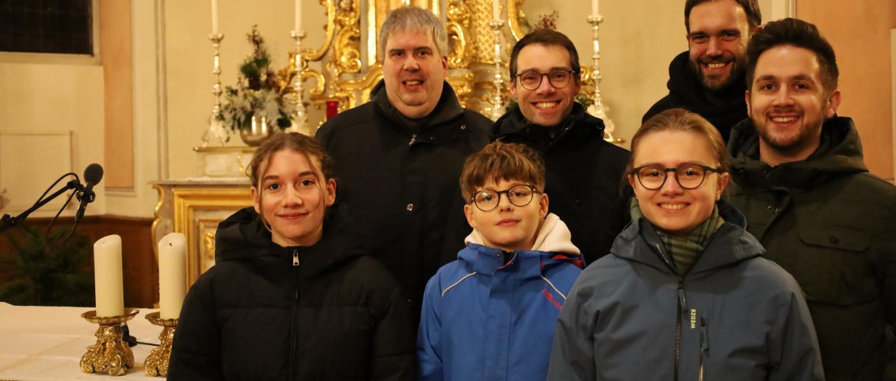 Teilnehmer des Gottesdienstes stehen vor dem Altarraum in der Kirche