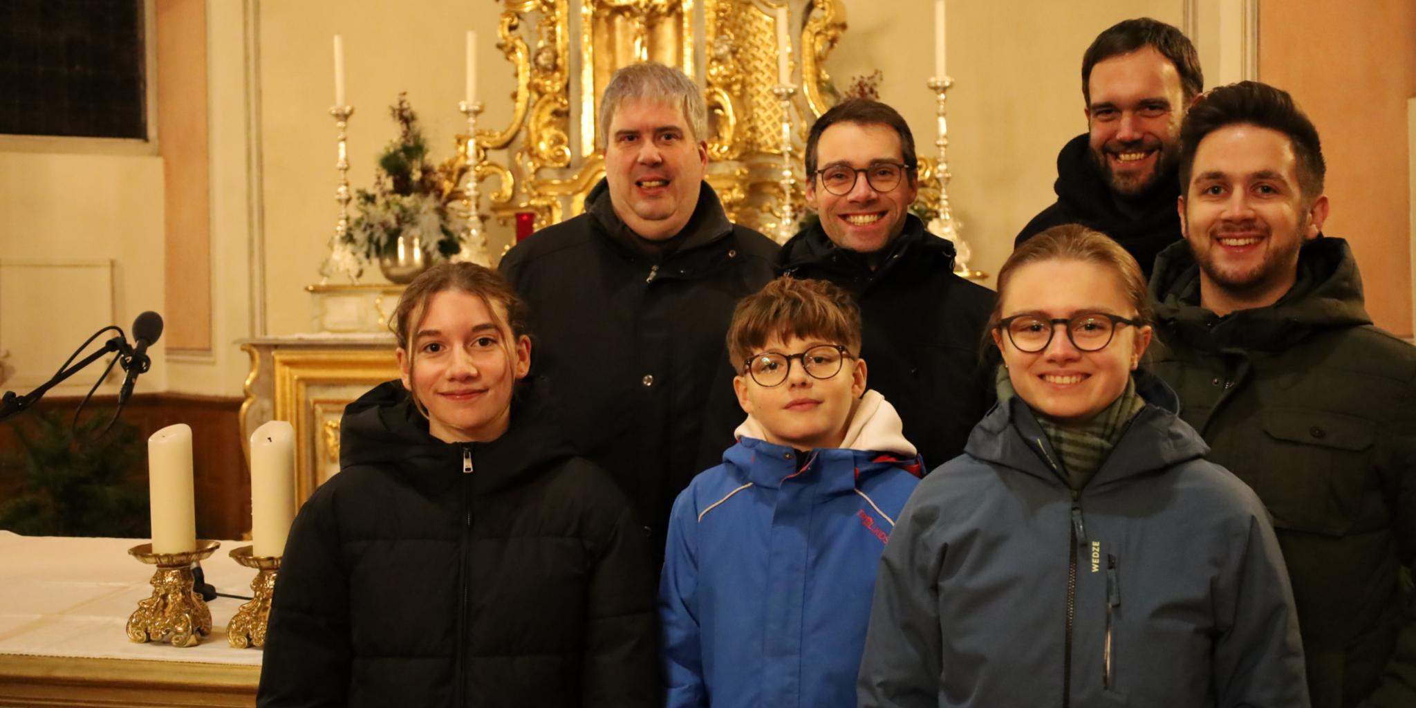 Teilnehmer des Gottesdienstes stehen vor dem Altarraum in der Kirche