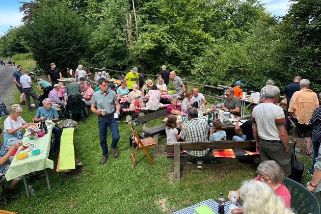 viele Menschen sitzen auf Bänken im Wald und machen ein Picknick