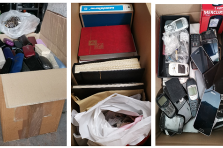 Kartons mit gesammelten Brillen, Briefmarkenalben und Handys