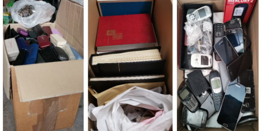 Kartons mit gesammelten Brillen, Briefmarkenalben und Handys