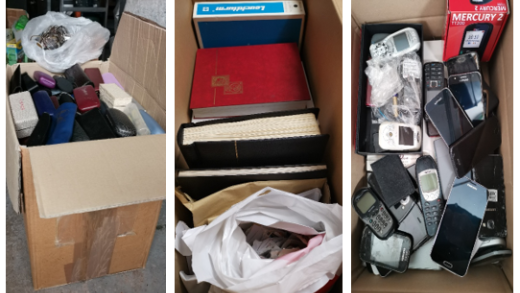 Kartons mit gesammelten Brillen, Briefmarkenalben und Handys