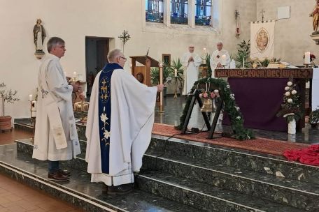Pastor und Diakone stehen im Altarraum und segnen die neue Glocke