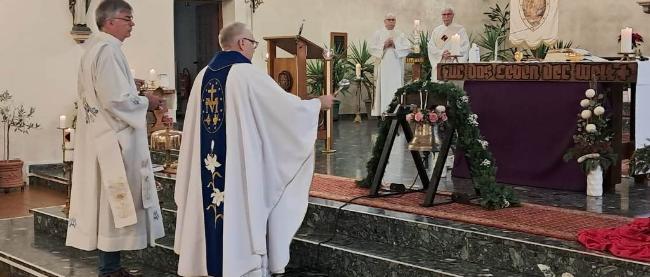 Pastor und Diakone stehen im Altarraum und segnen die neue Glocke