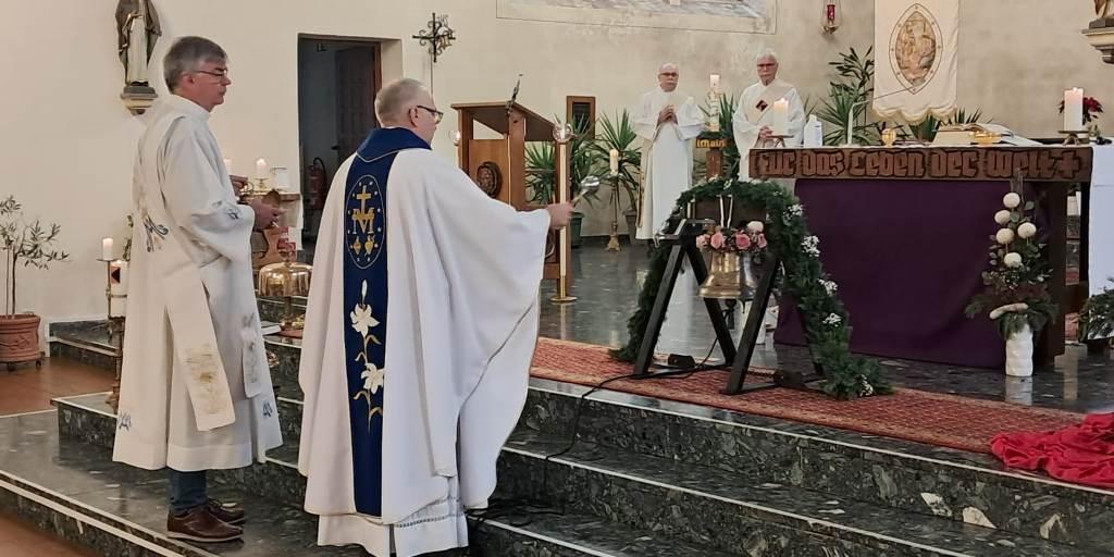 Pastor und Diakone stehen im Altarraum und segnen die neue Glocke