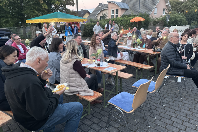 Menschen sitzen draußen auf Bierbänken, hören Musik, sind am Essen und haben eine gute Zeit