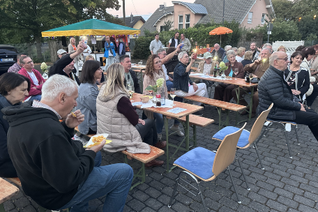 Menschen sitzen draußen auf Bierbänken, hören Musik, sind am Essen und haben eine gute Zeit