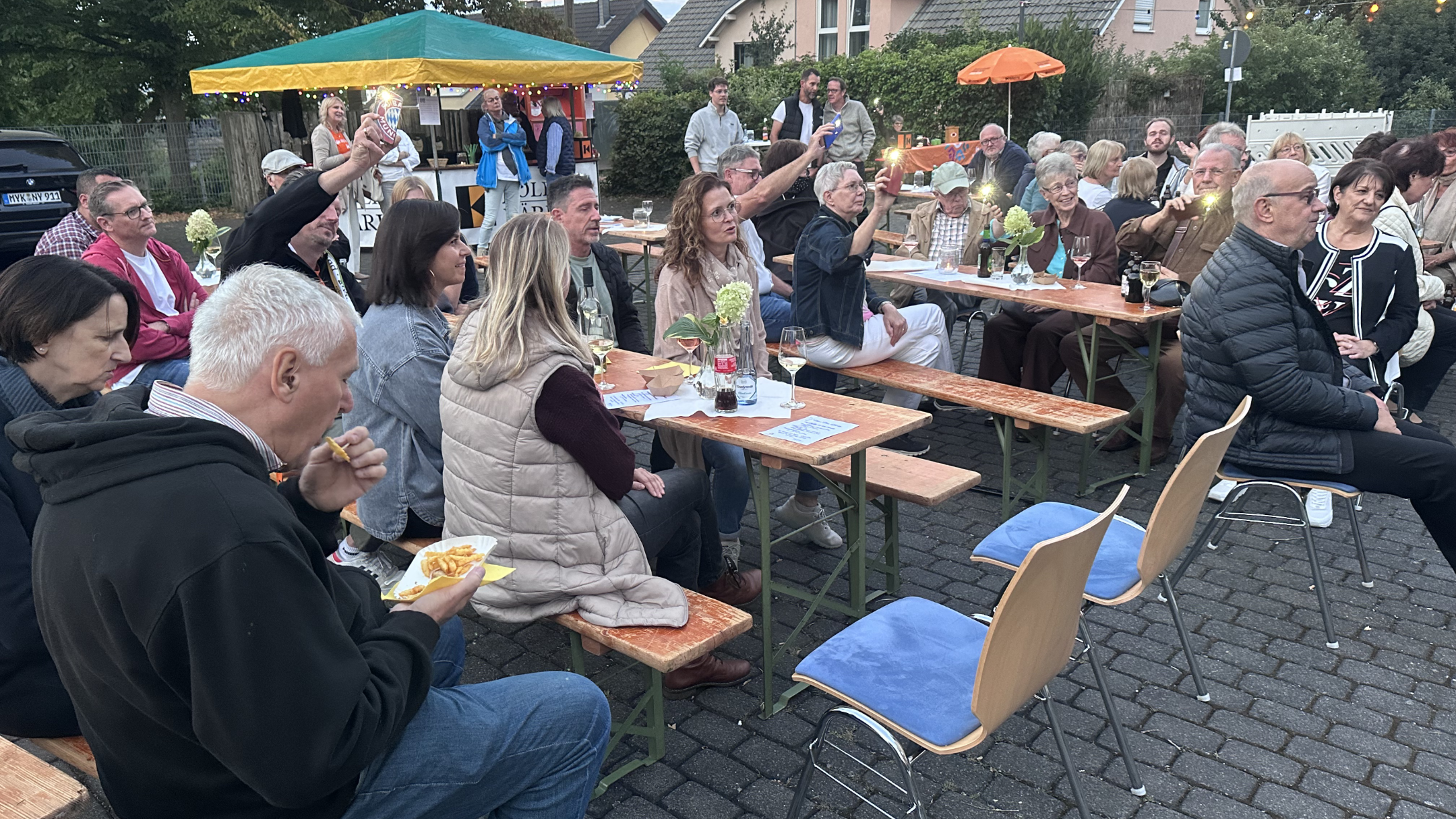 Menschen sitzen draußen auf Bierbänken, hören Musik, sind am Essen und haben eine gute Zeit