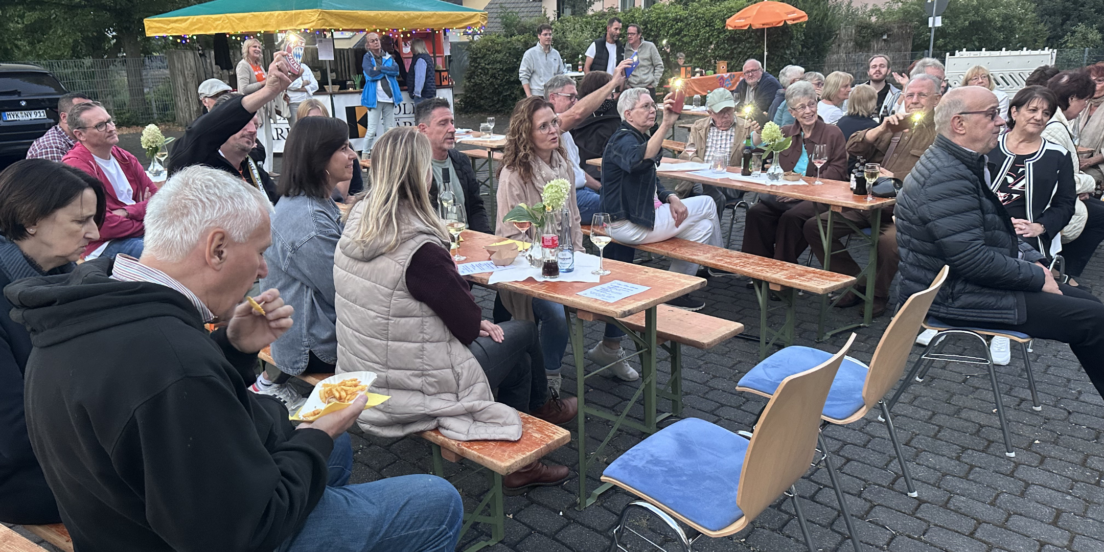 Menschen sitzen draußen auf Bierbänken, hören Musik, sind am Essen und haben eine gute Zeit (c) Kolpingsfamilie St. Mauritius Kärlich Menschen sitzen draußen auf Bierbänken, hören Musik, sind am Essen und haben eine gute Zeit